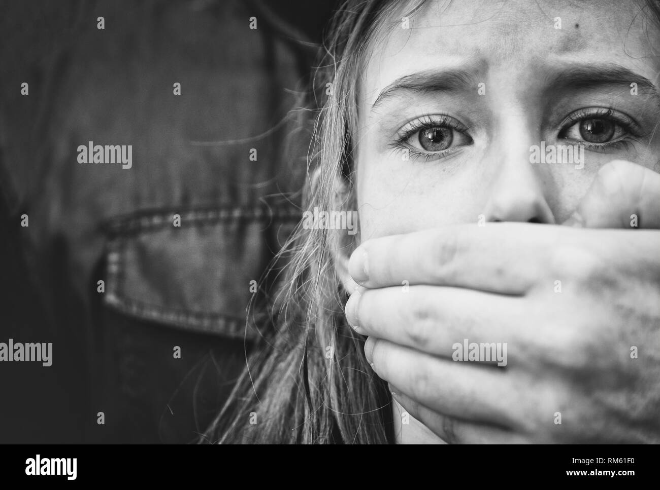Man's hand covering mouth of scared young girl. Stock Photo
