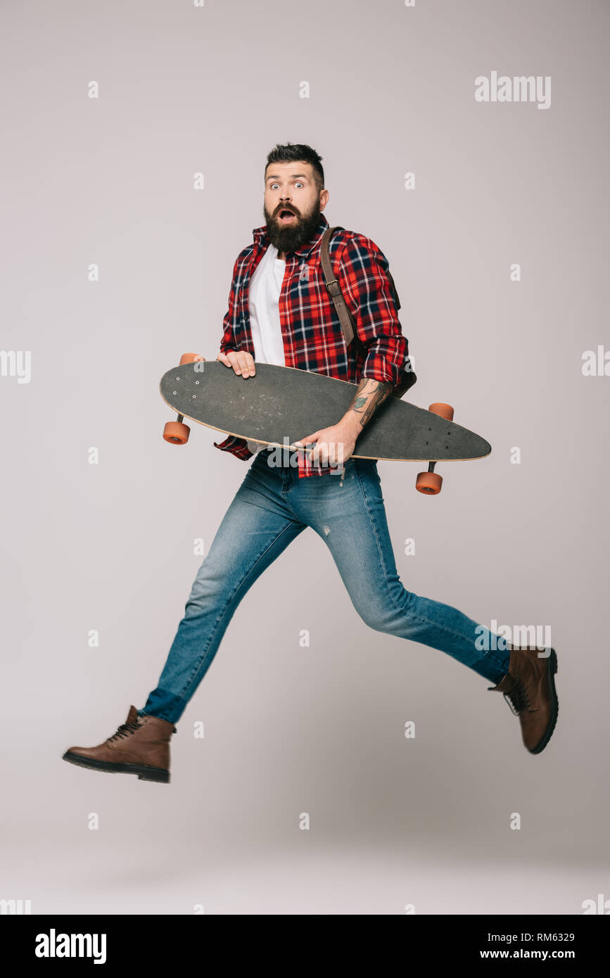 excited man jumping with longboard isolated on grey Stock Photo