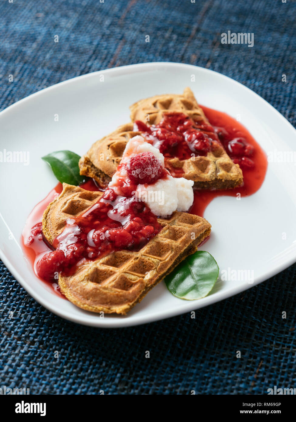 Heart shaped vegan beet waffles with a raspberry sauce. Stock Photo