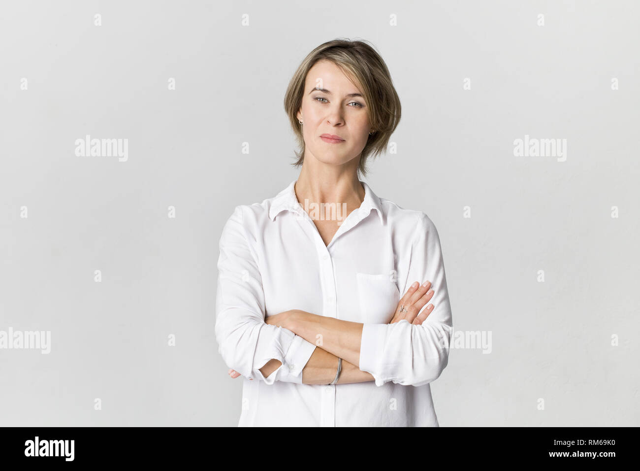 Serious businesswoman standing with arms crossed. Confidence woman in white shirt isolated on white Stock Photo