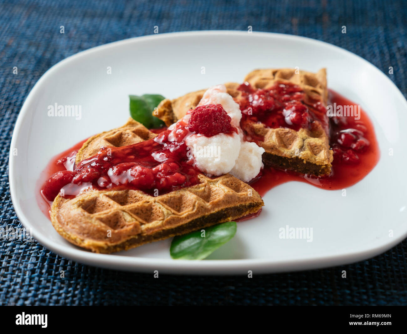 Heart shaped vegan beet waffles with a raspberry sauce. Stock Photo