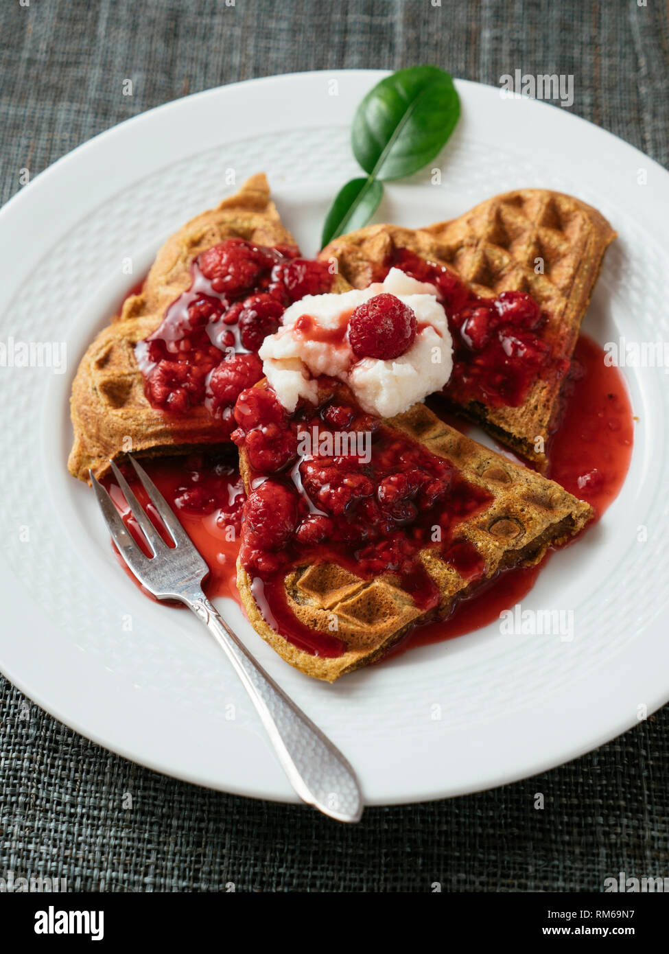 Heart shaped vegan beet waffles with a raspberry sauce. Stock Photo
