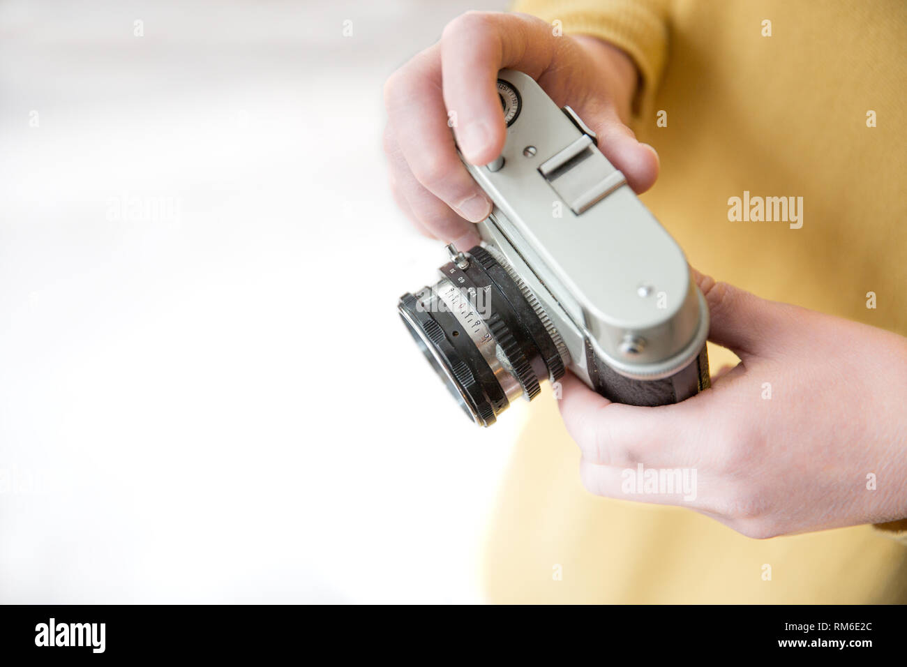A midsection of a female photographer wearing yellow and holding a vintage, 35mm camera with copy space in a hobby lifestyle image Stock Photo