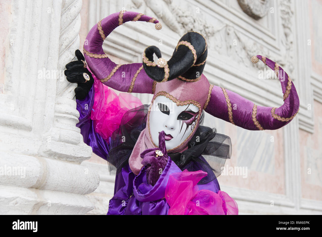 A poser in Venice during Venice Carnival. He is wearing a decorated mask and a purple outfit complete with horns. The Carnival dates from about 1162. Stock Photo