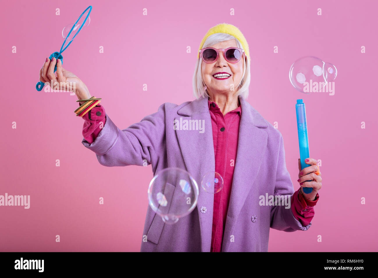 Lovely elderly lady wearing purple coat and yellow head band Stock Photo