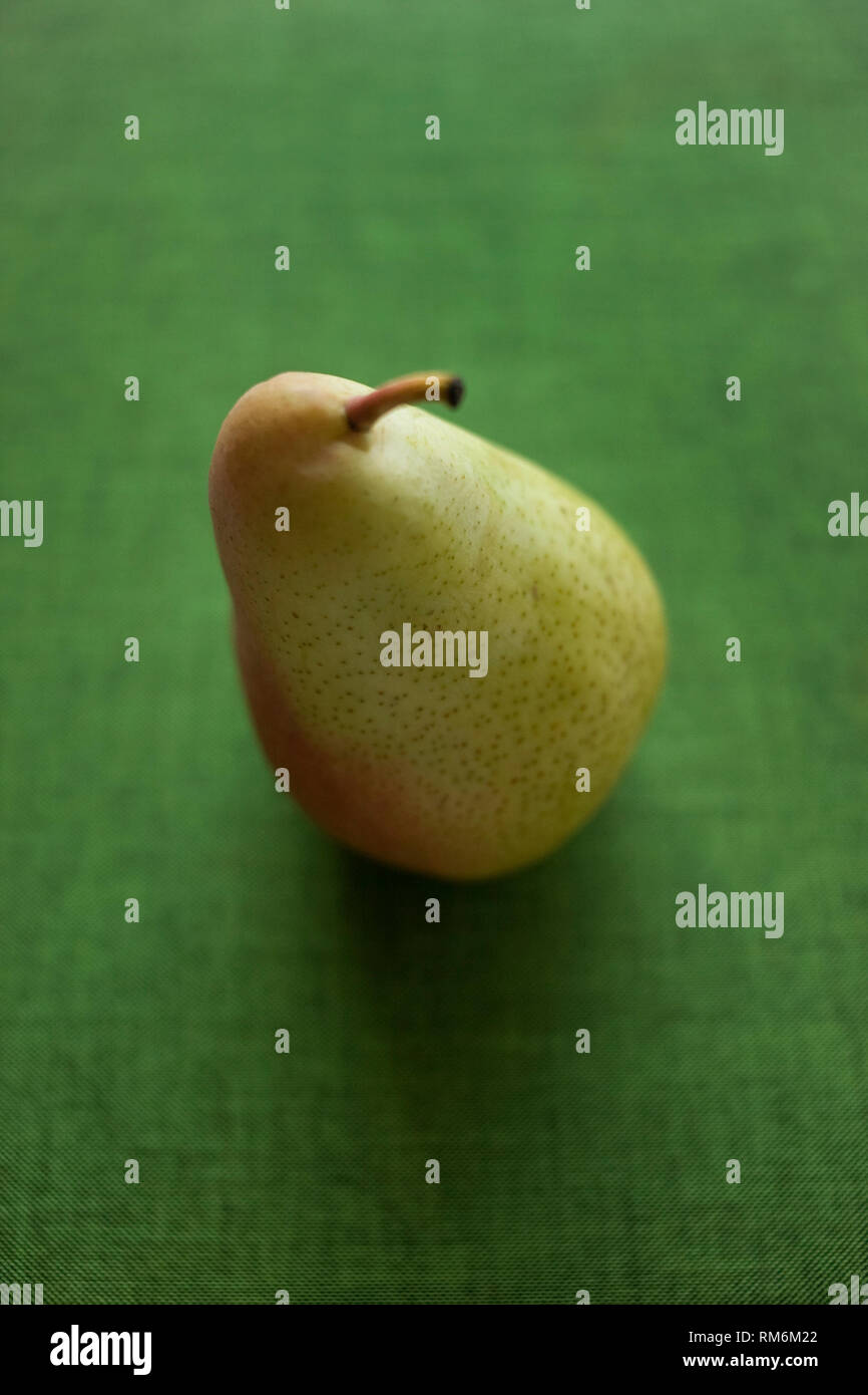 A Single Pear On A Green Textured Background Stock Photo