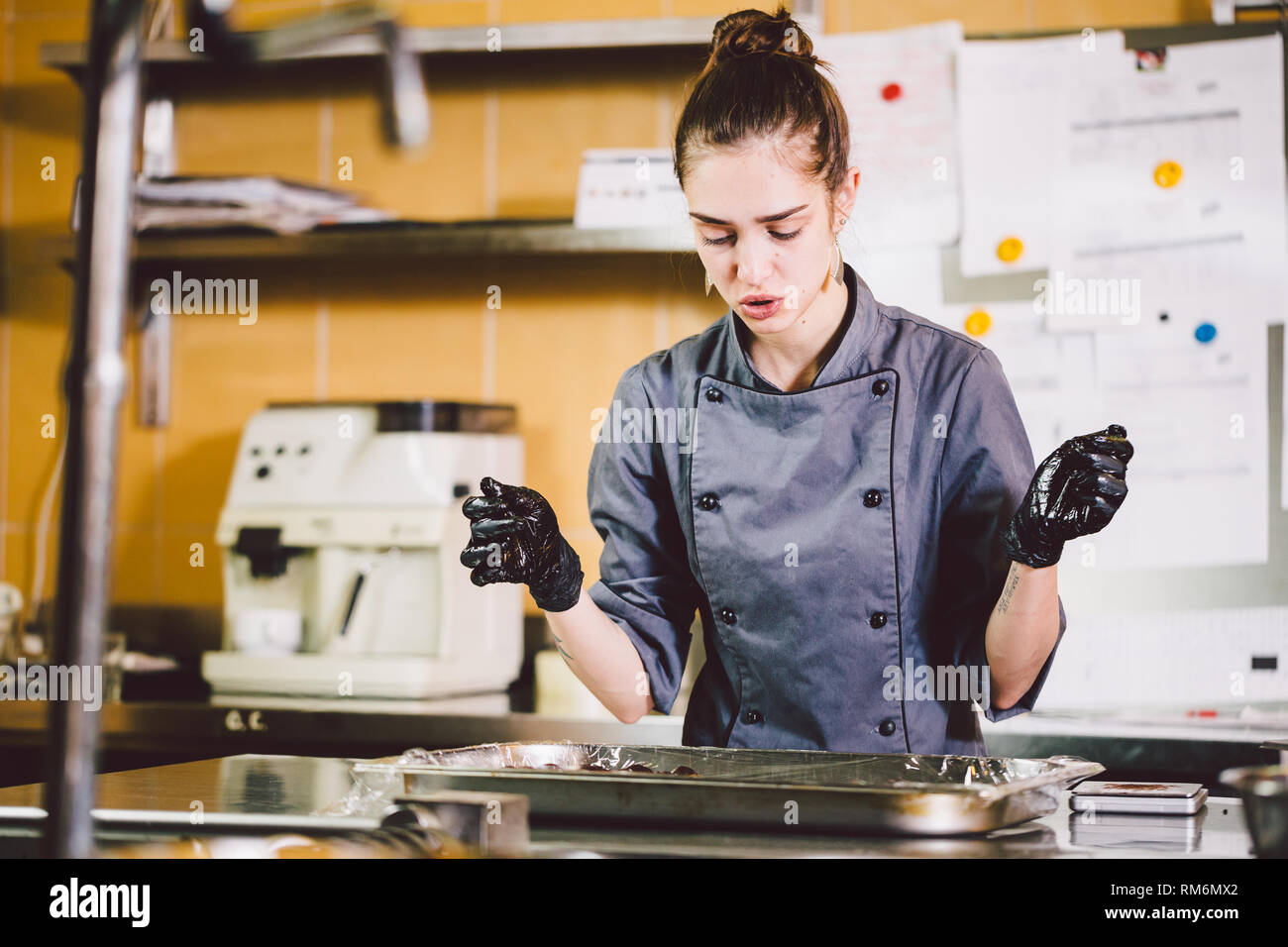 Subject profession and cooking pastry. young Caucasian woman with tattoo of  pastry chef in kitchen of restaurant preparing round chocolate candies han  Stock Photo - Alamy