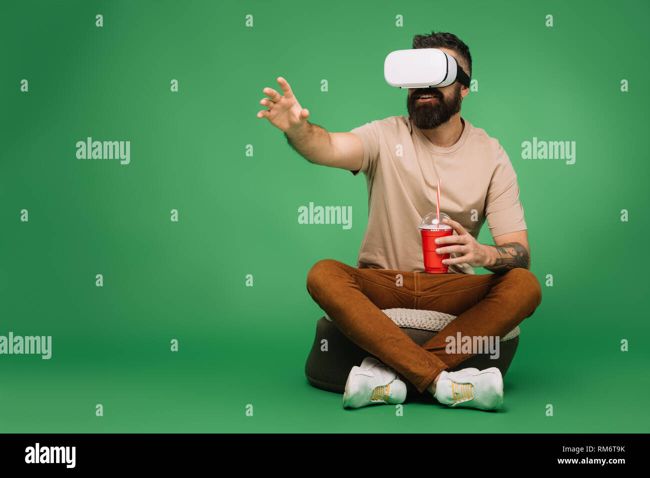 bearded man with soda using Virtual reality headset isolated on green Stock Photo