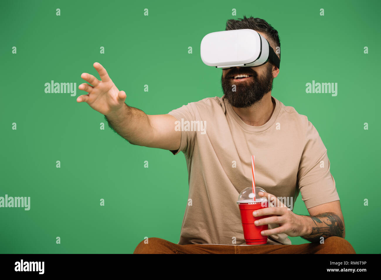 smiling man with soda using Vr headset isolated on green Stock Photo