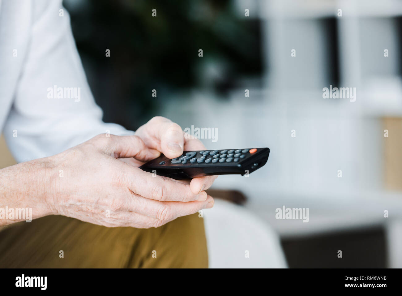 cropped view of senior man holding remote control in hands Stock Photo