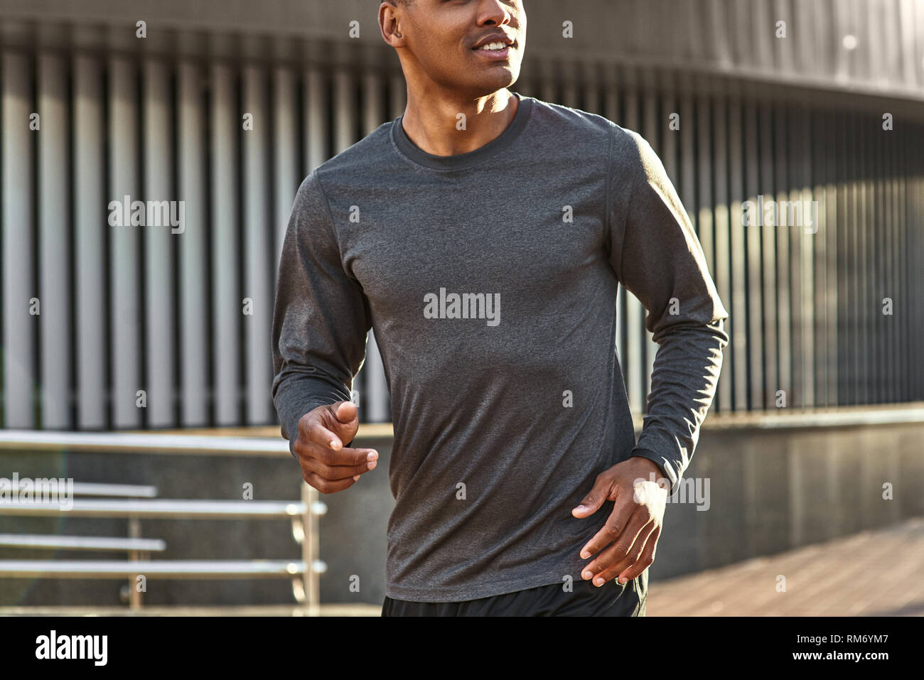 Happy to be healthy. Close-up portrait of handsome and positive african man in sportswear starting to run during his morning workout. Cardio training. Urban workout. Sport motivation concept. Stock Photo