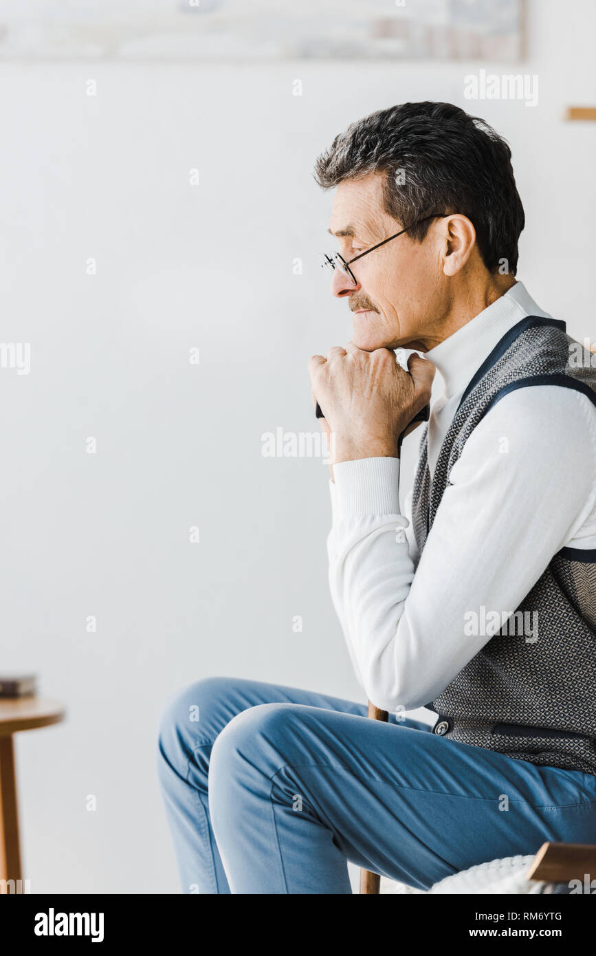 sad pensioner sitting on sofa at home Stock Photo