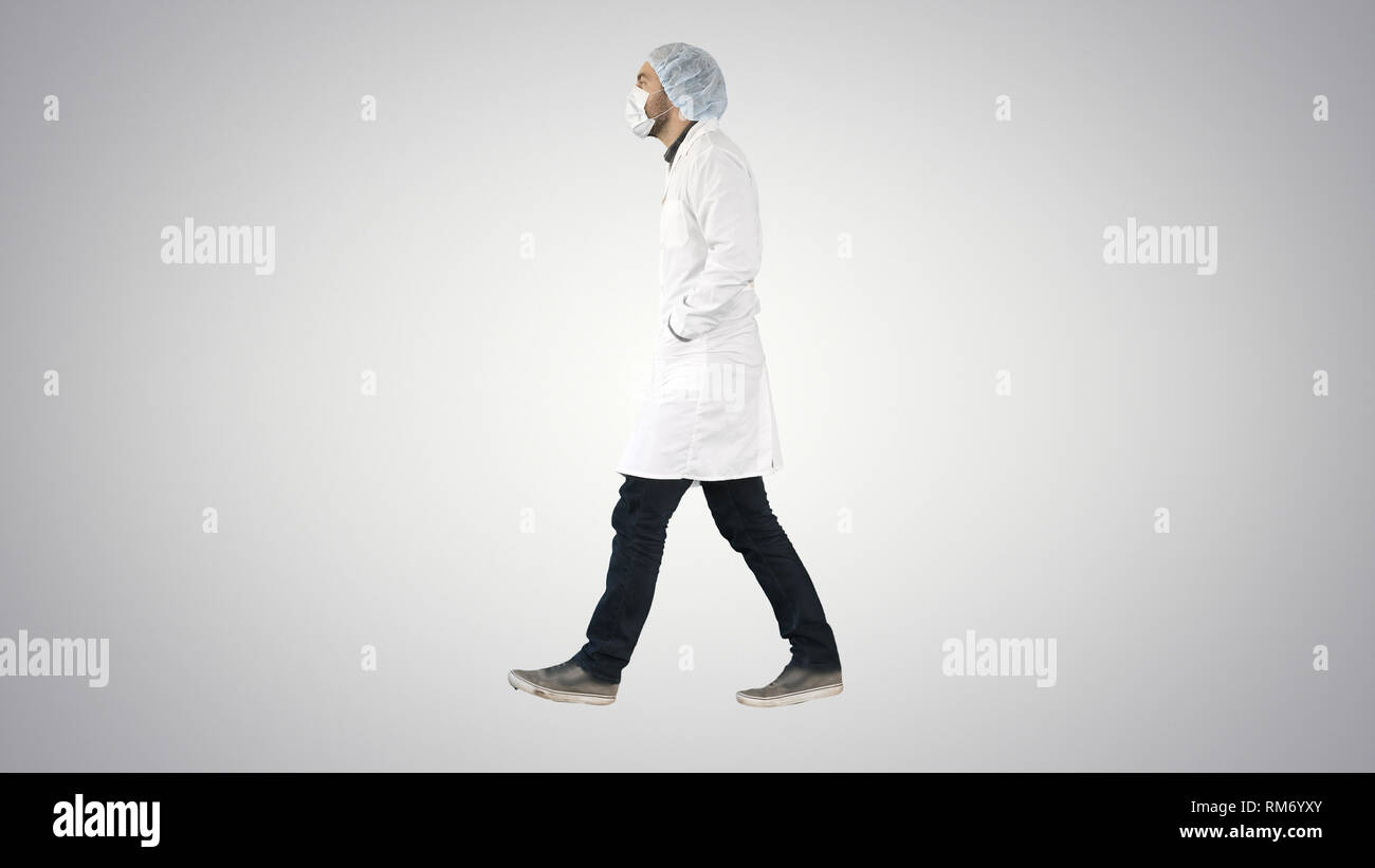 Walking doctor puting medical mask on on gradient background. Stock Photo