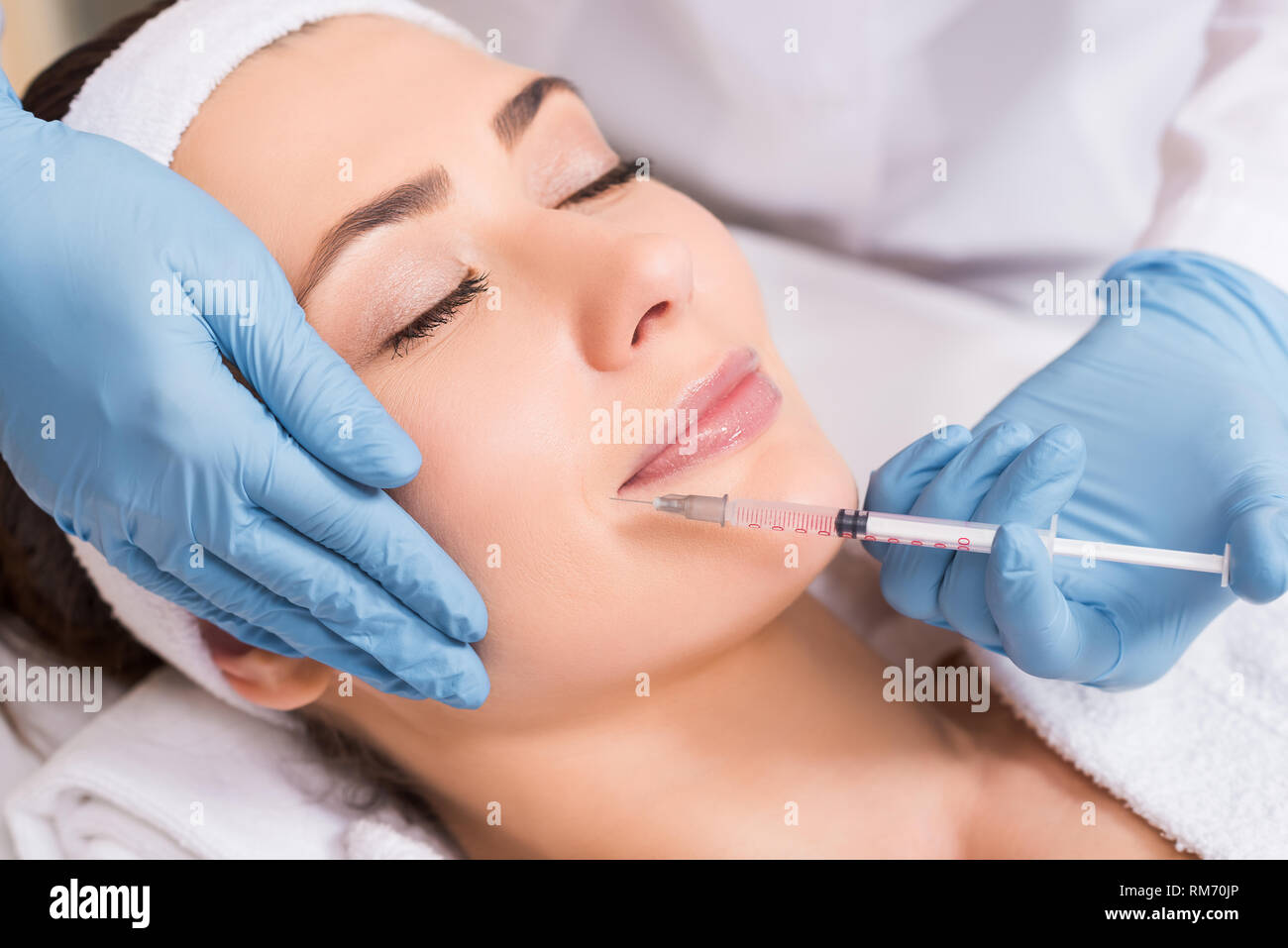 cosmetologist making injection on face to woman at beauty salon Stock