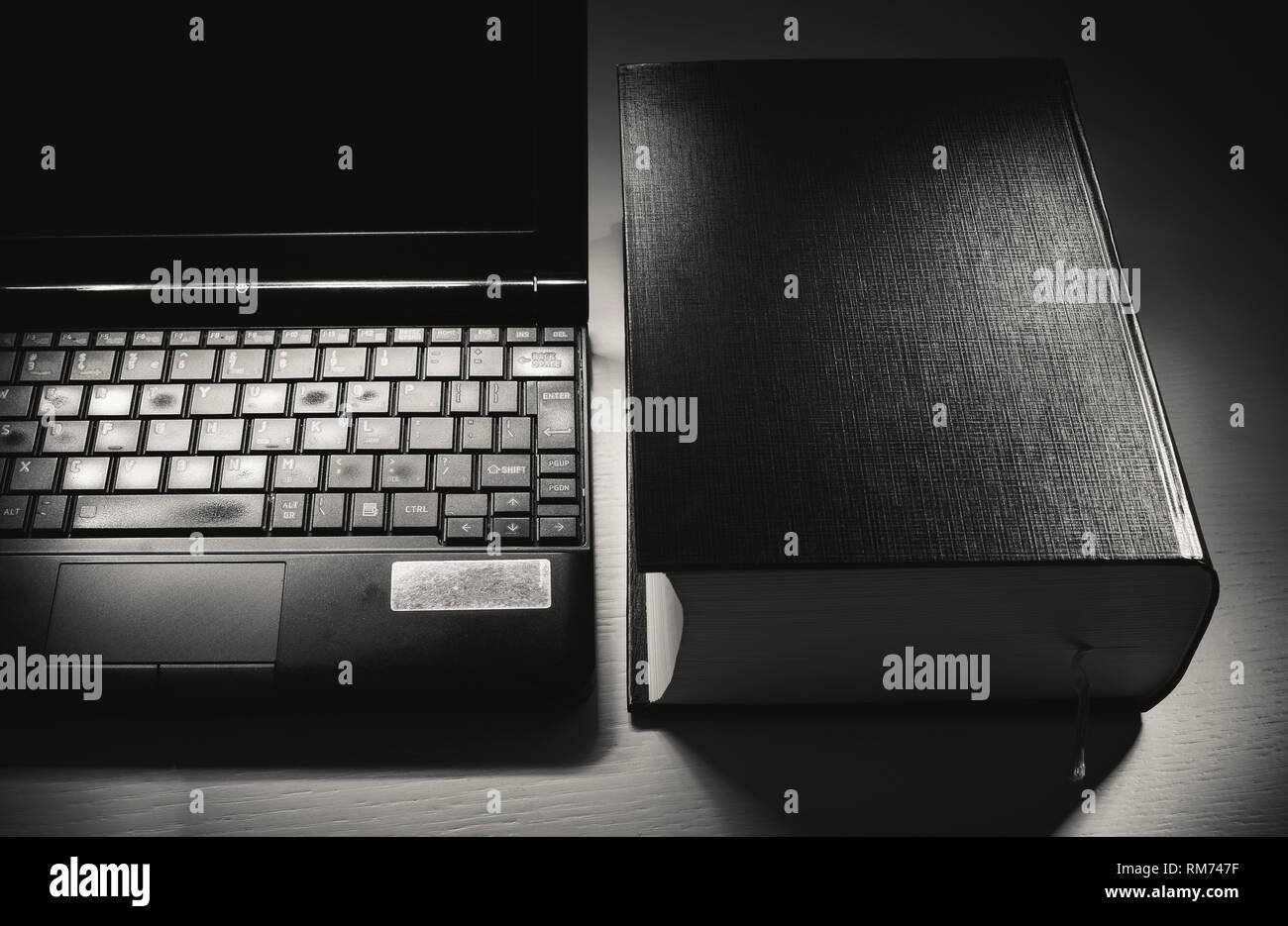 Conceptual composition about knowledge, old opened laptop and book. Stock Photo