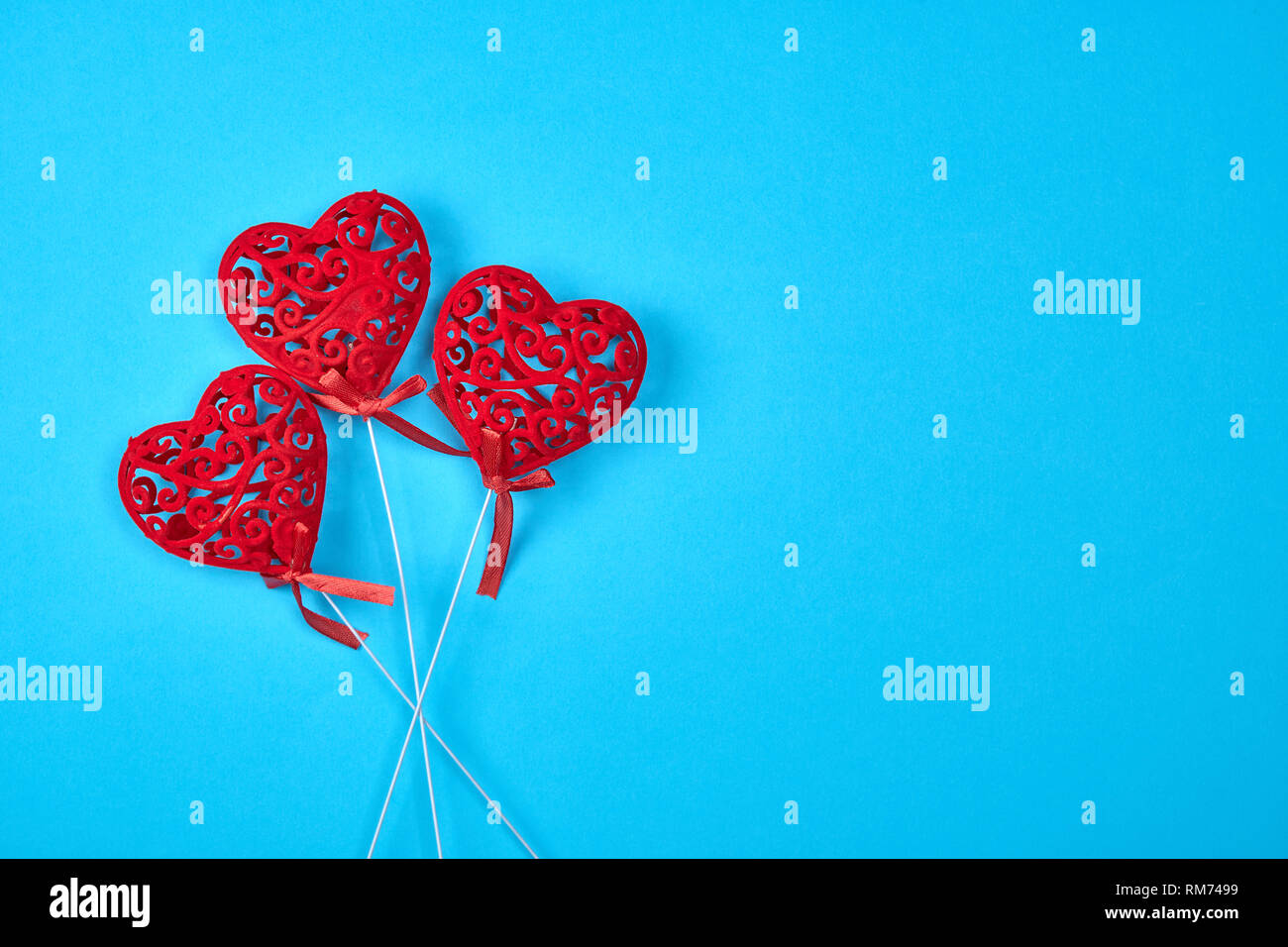 three red carved hearts on a stick on a blue background,  copy space Stock Photo