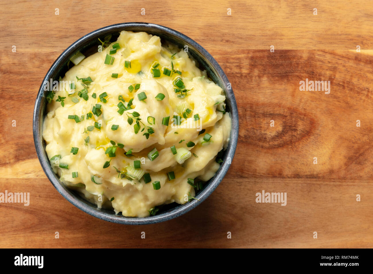 Pomme puree, an overhead photo of a bowl of mashed potatoes with herbs, shot from the top on a rustic wooden background with copy space Stock Photo
