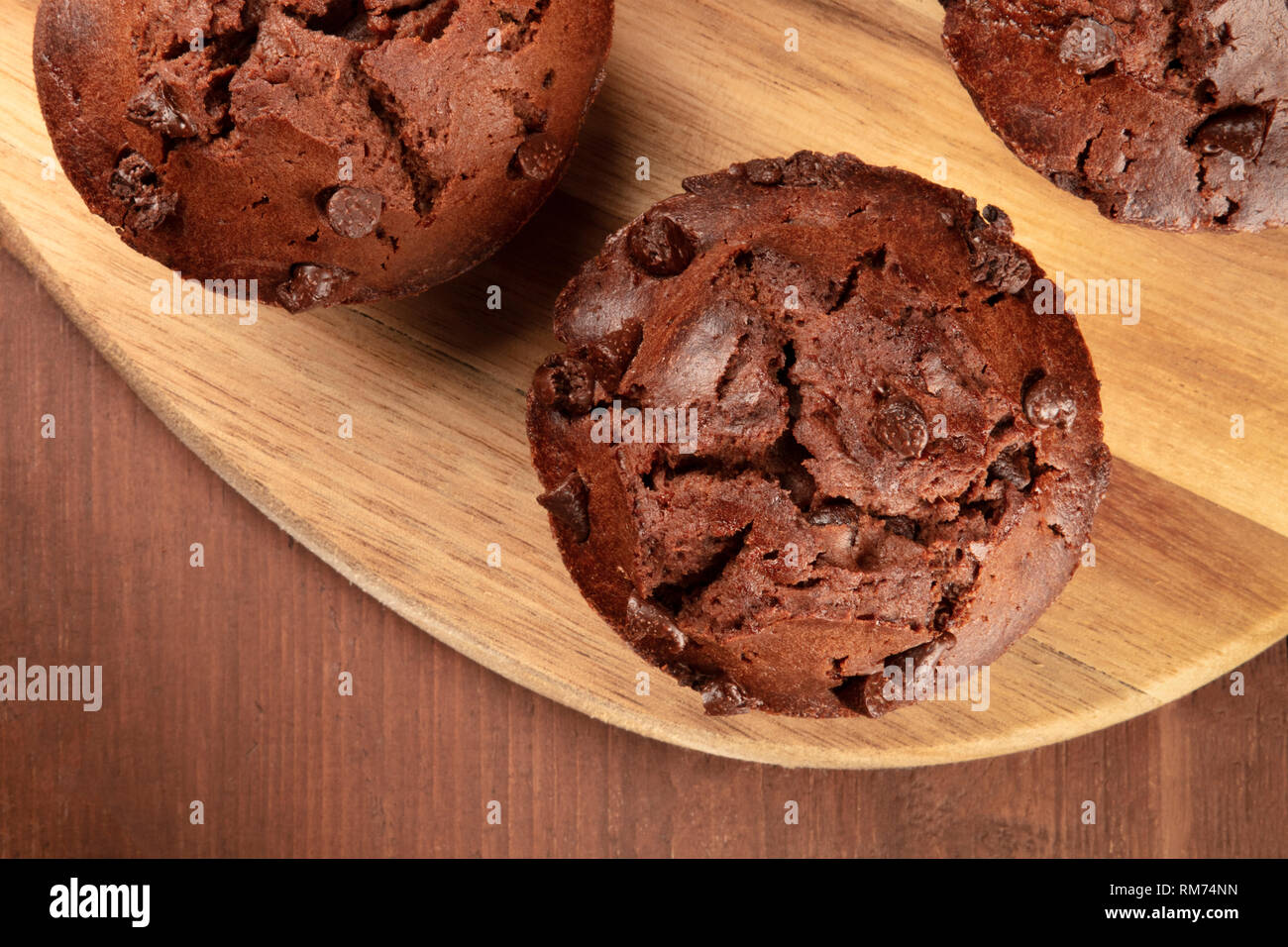 An overhead closeup photo of chocolate muffins on a dark rustic wooden ...