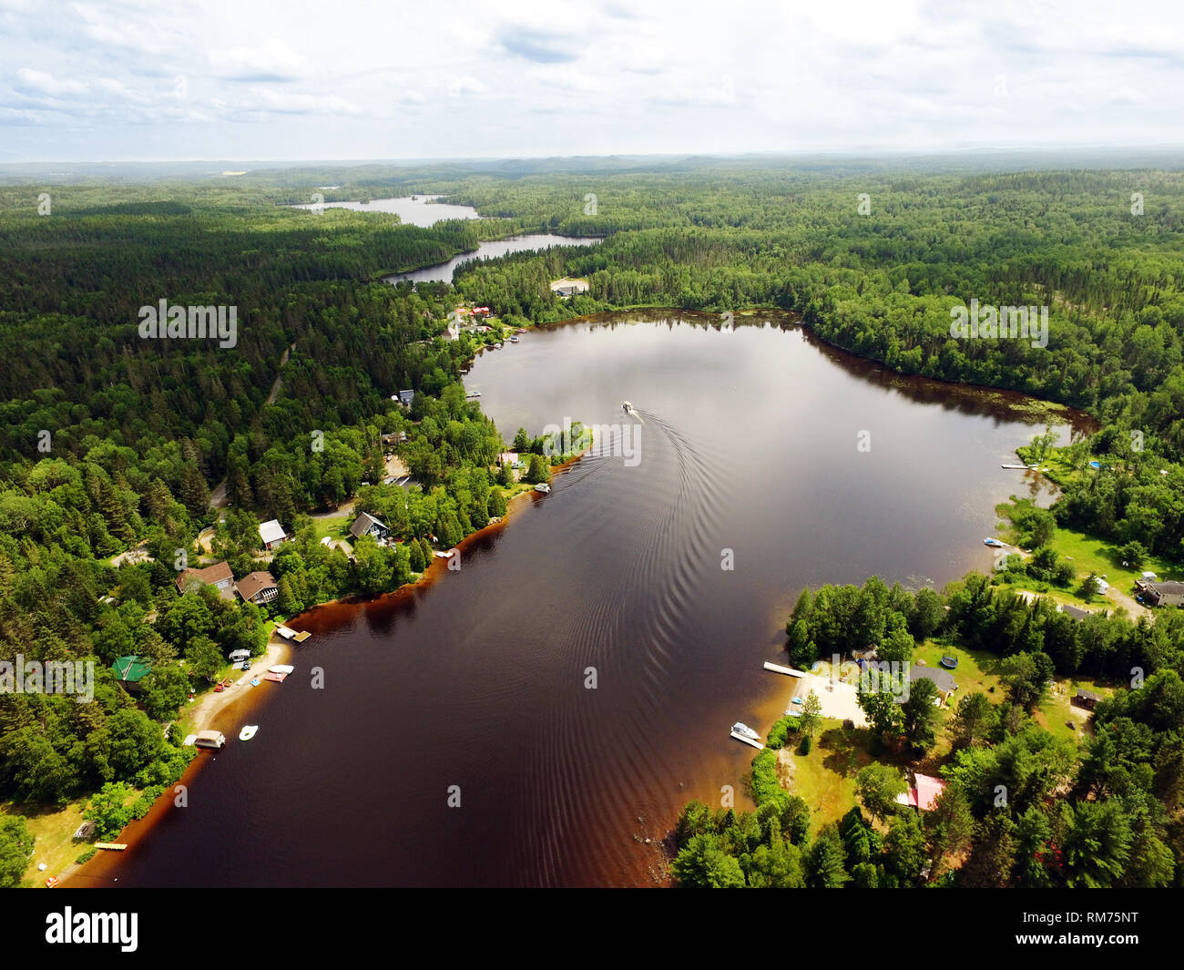 Aerial view of small Canadian lake with cottages and boat Stock Photo