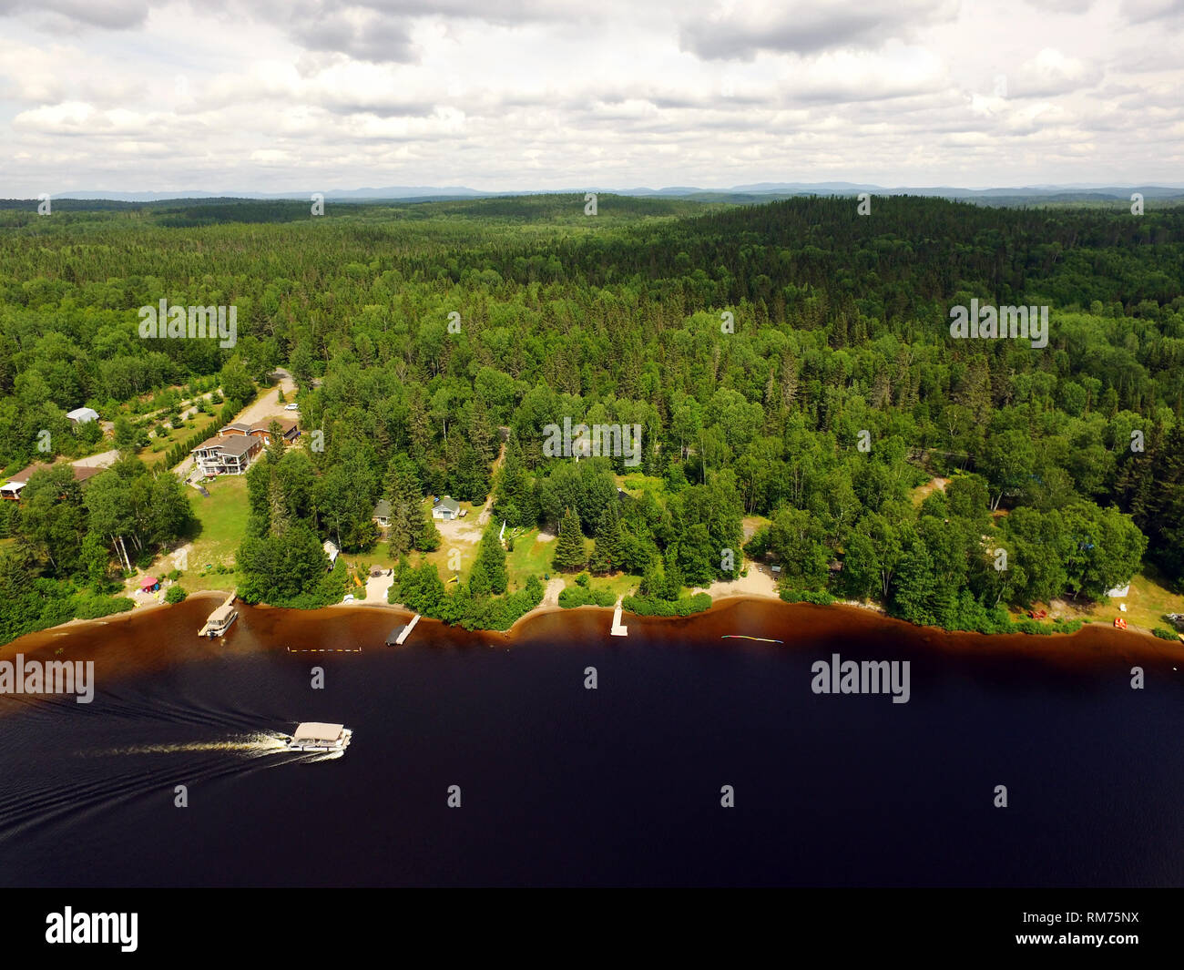Aerial view of forest lake with cottages and ponton cruising by Stock Photo