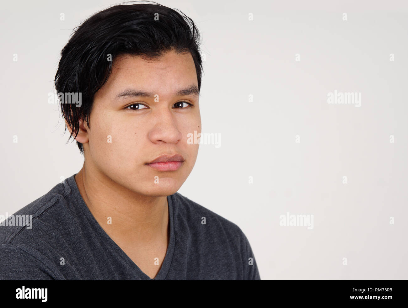 Portrait of teenage latino boy with neutral expression on white Stock Photo