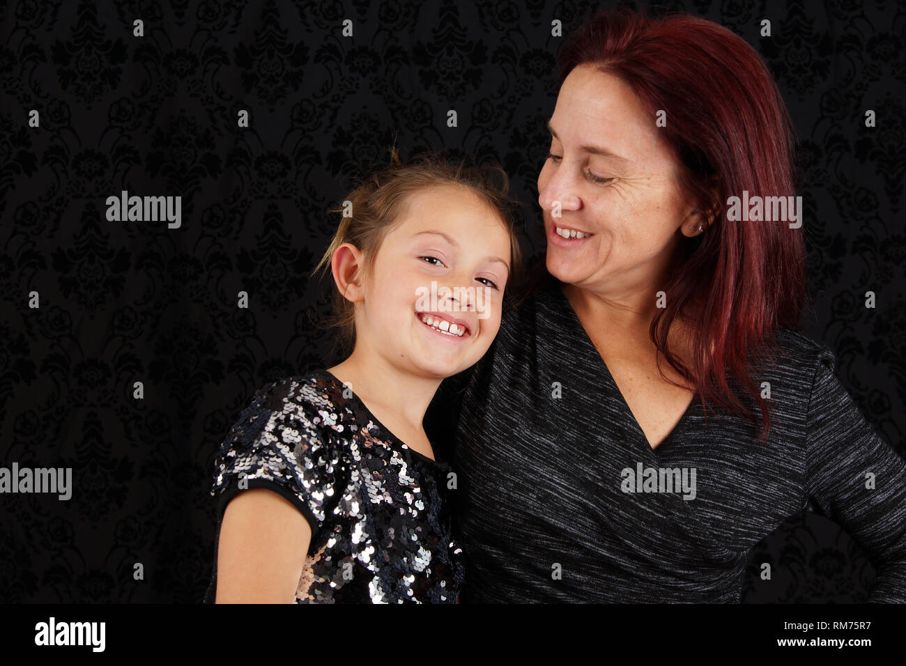 Cute candid mother daughter portrait over black background Stock Photo