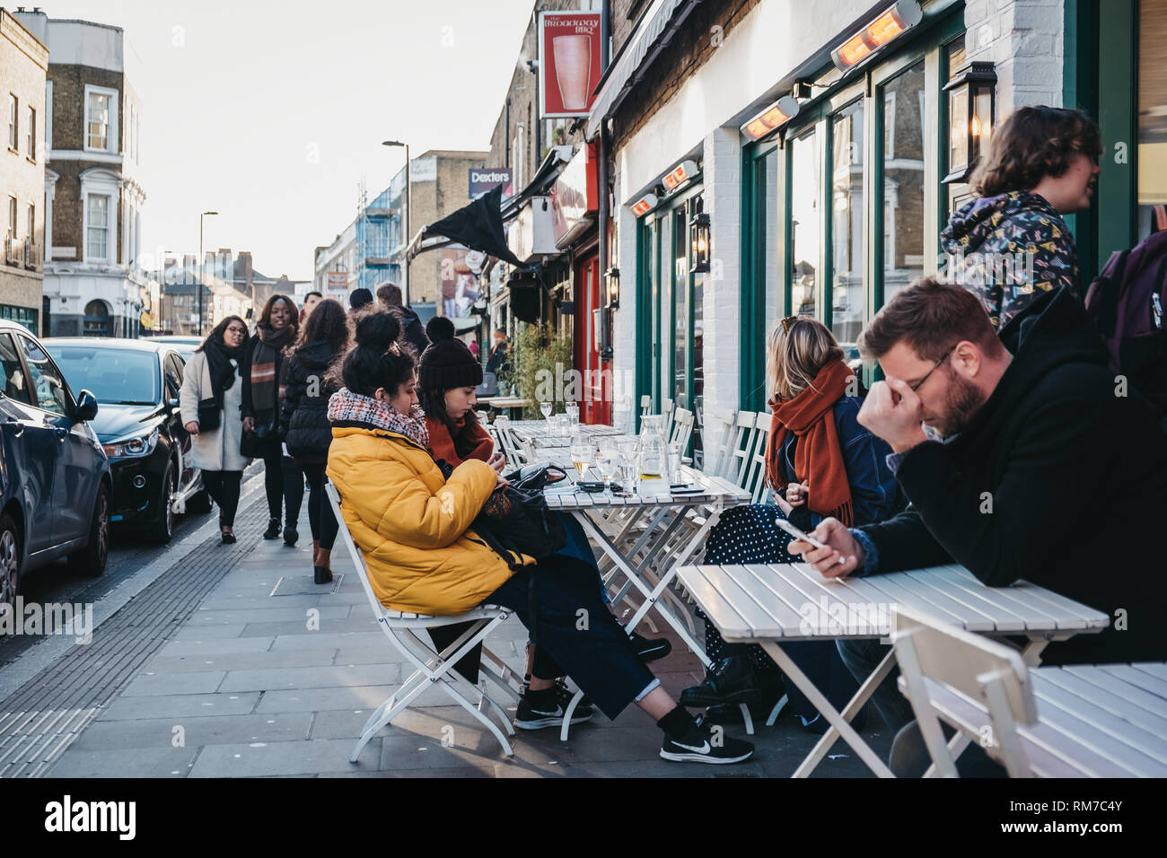 London, UK - February 03, 2019: People sitting at an outdoor table of a cafe on Broadway Market, a shopping street in the heart of Hackney, East Londo Stock Photo