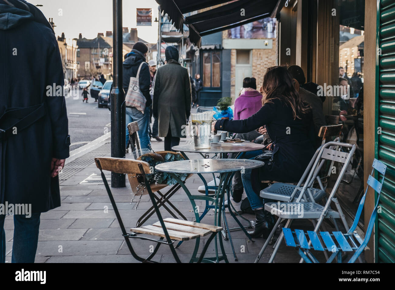 London, UK - February 03, 2019: People sitting at an outdoor table of a cafe on Broadway Market, a shopping street in the heart of Hackney, East Londo Stock Photo