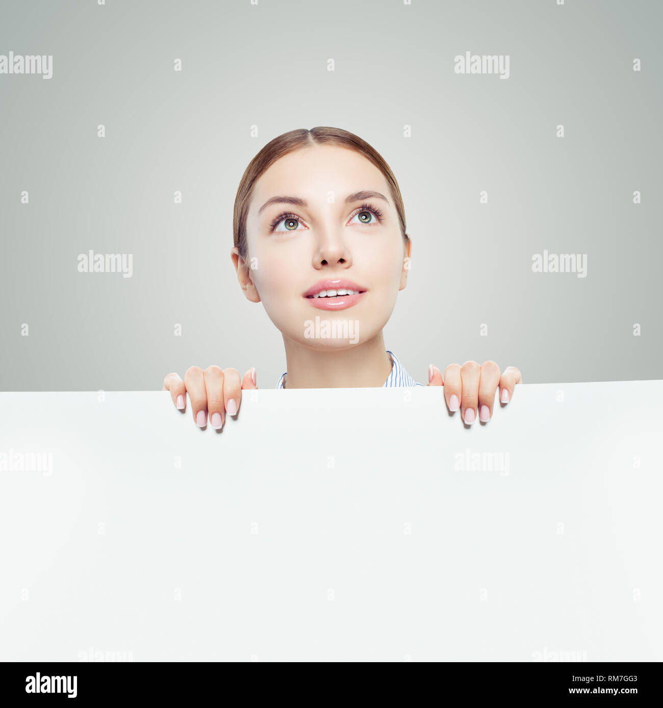 Happy woman looking up and holding white empty paper board background with copy space for advertising marketing or product placement Stock Photo