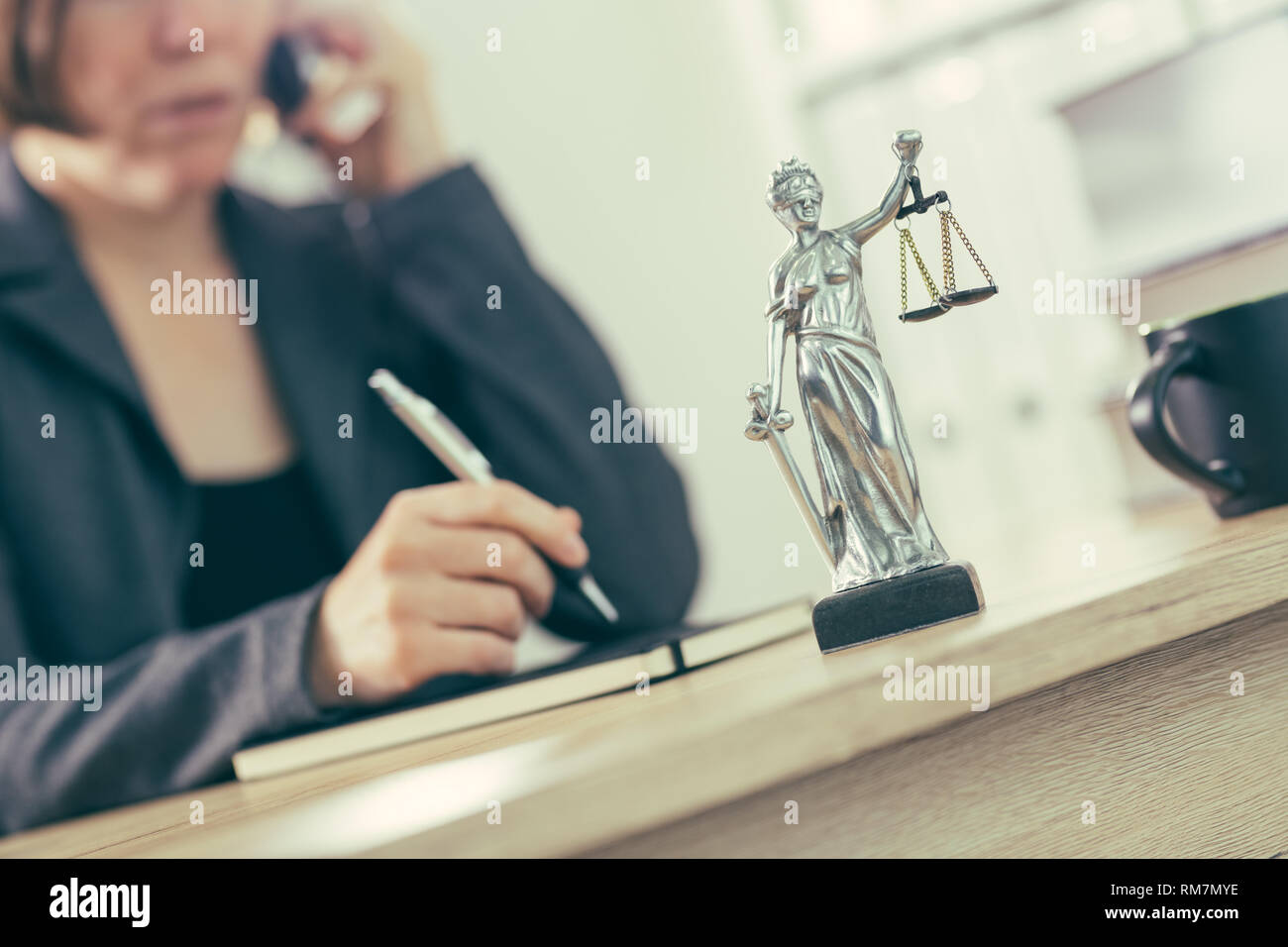 Attorney woman talking on mobile phone from her office desk, selective focus Stock Photo
