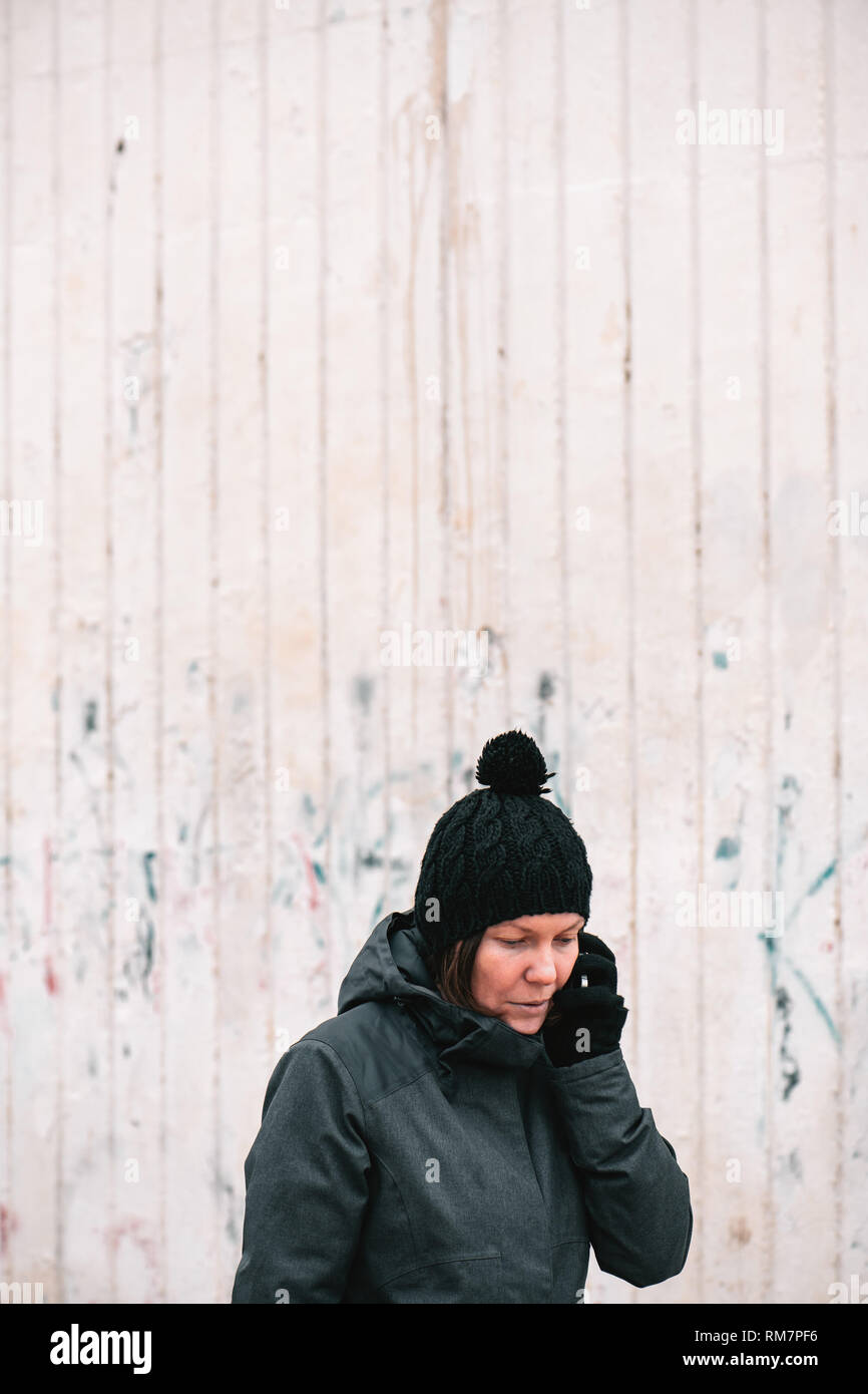 Worried troubled woman talking on mobile phone out on street on a cold winter day Stock Photo