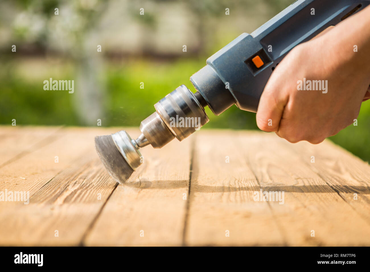 Hands man with electrical rotating brush metal disk sanding a piece of