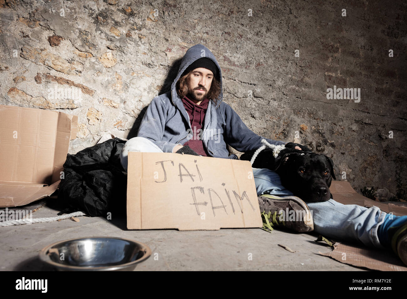 Clochard with dog and cardboard sign on the street Stock Photo