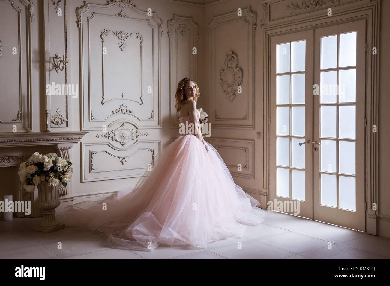Beautiful young blond woman in luxurious long pink dress posing in ...