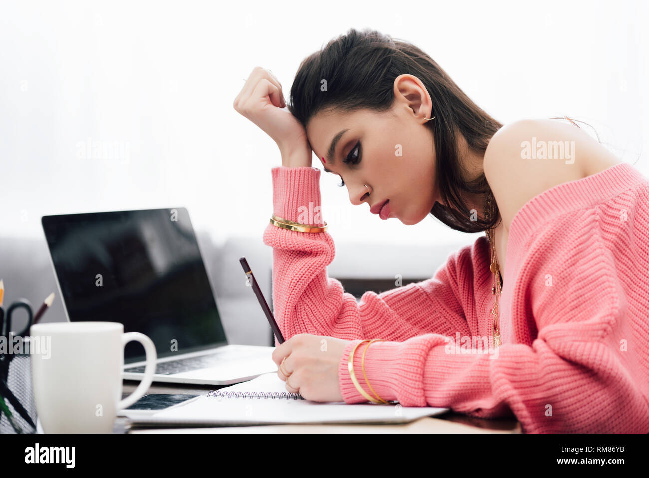 beautiful indian woman studying and writing in notebook at table with ...