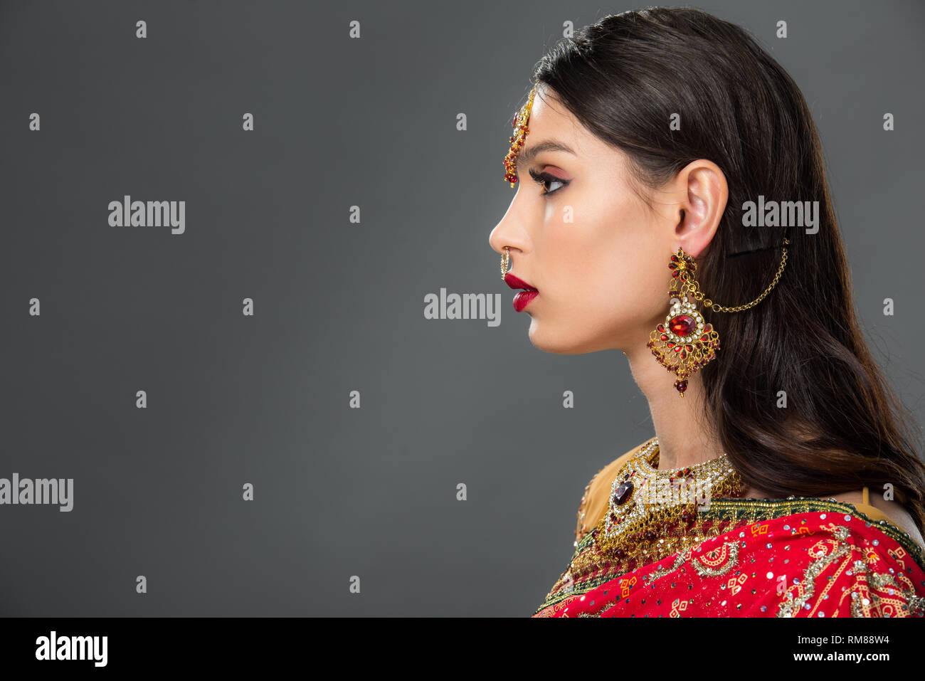 side view of attractive indian woman posing in traditional sari and bindi, isolated on grey Stock Photo