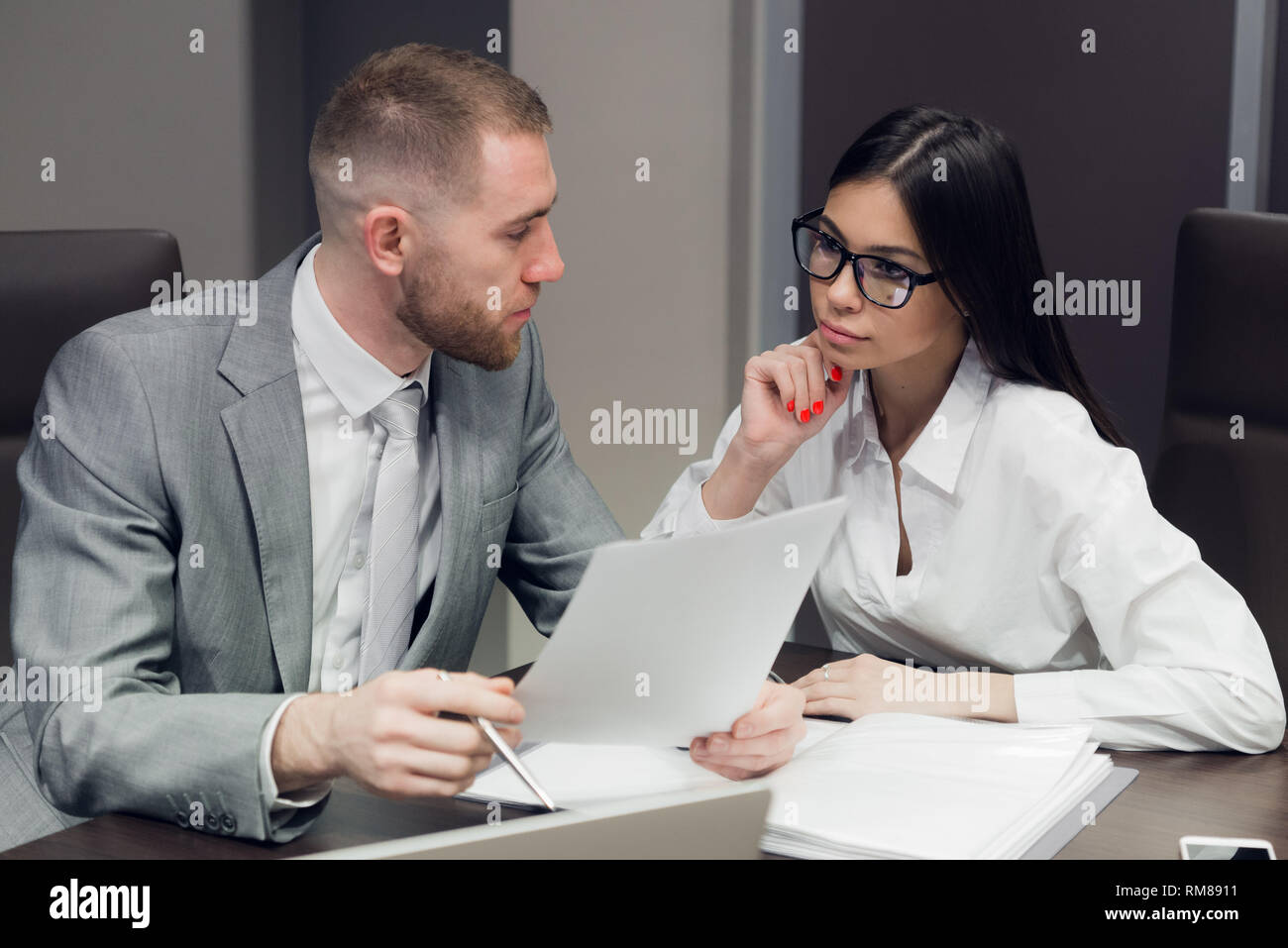 Two young business people discussing work during a business presentation in conference room Stock Photo
