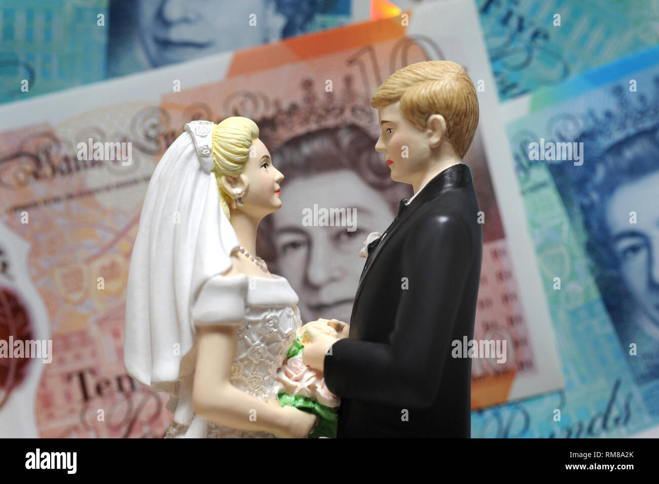BRIDE AND GROOM FIGURES WITH BRITISH BANKNOTES RE WEDDING COSTS MARRIAGE DIVORCE LAWYERS FIRST TIME HOUSE BUYERS ETC UK Stock Photo