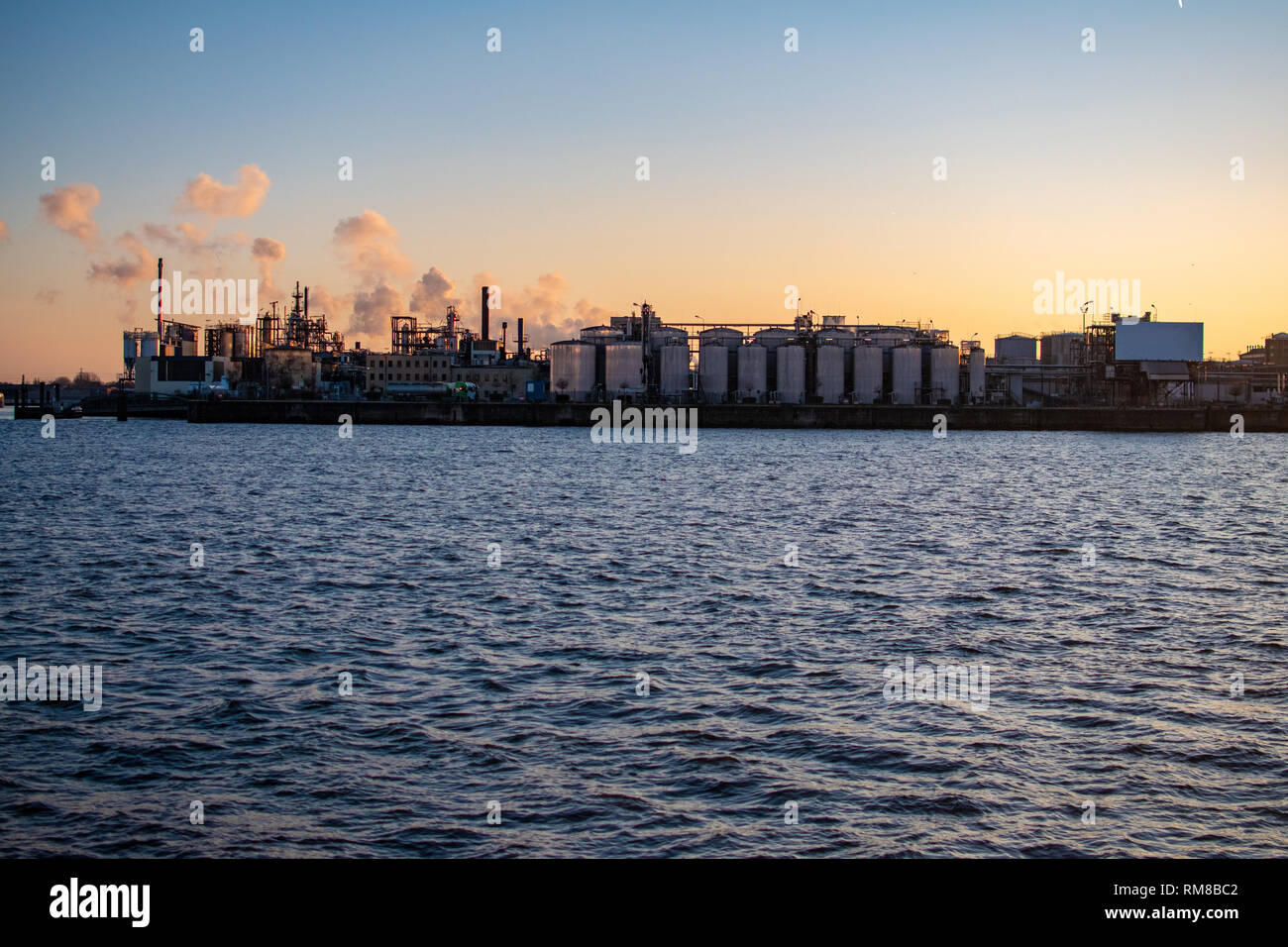 Panorama of industrial cityscape with metallurgical and chemical plants and big . Smoke pipes emissions. A background of an orange-colored sky Stock Photo
