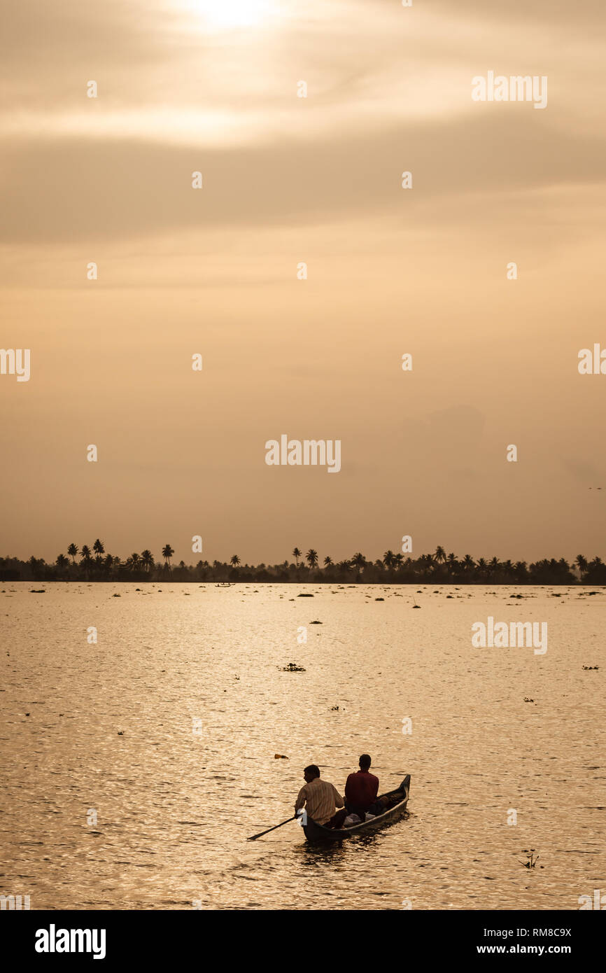 man paddling standing up in dugout canoe in sunrise lit water travels
