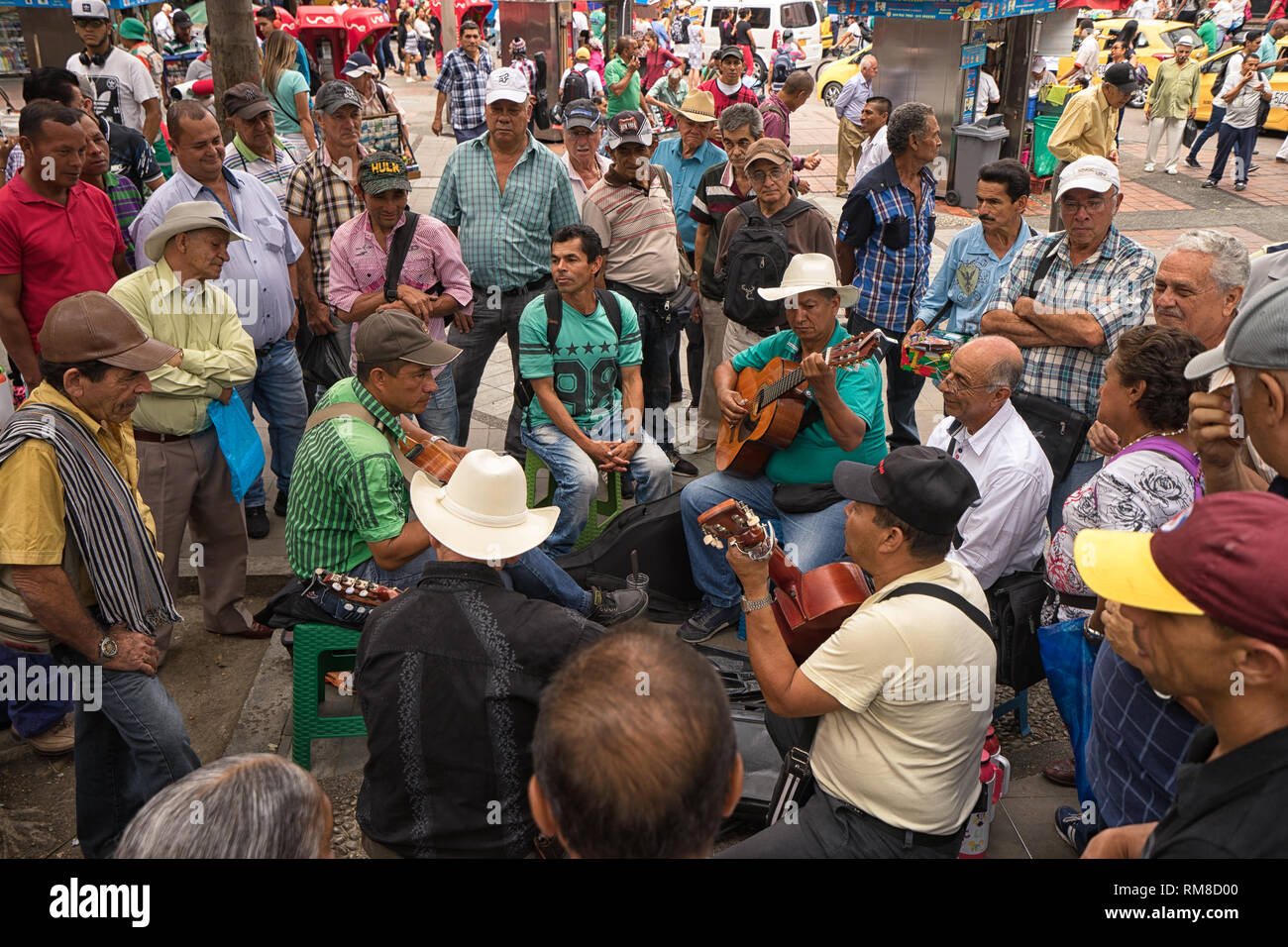 Medellin, Colombia - July 23, 2018: men playing guitars in a park surrounded by people Stock Photo