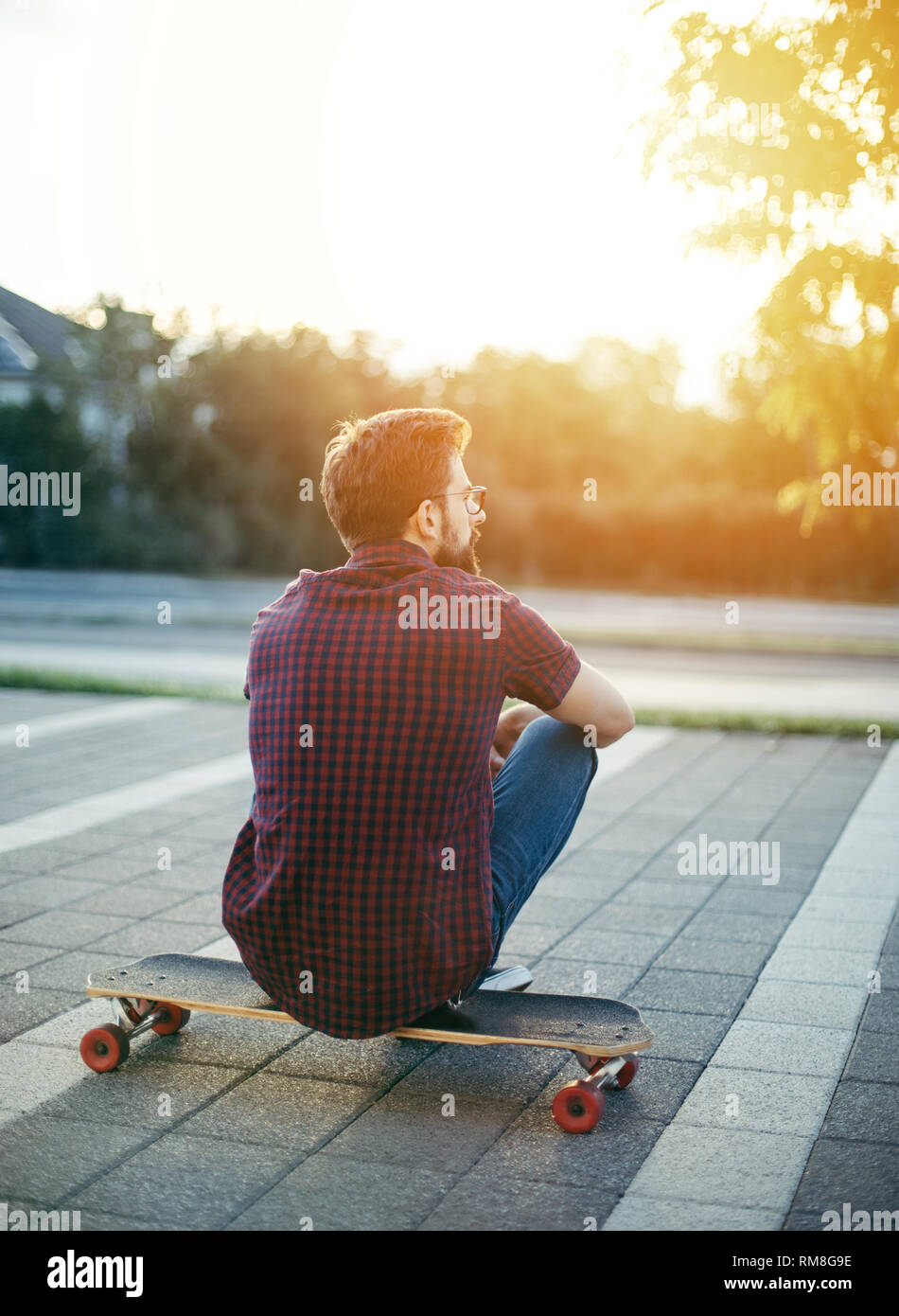 Man sitting on his longboard Stock Photo