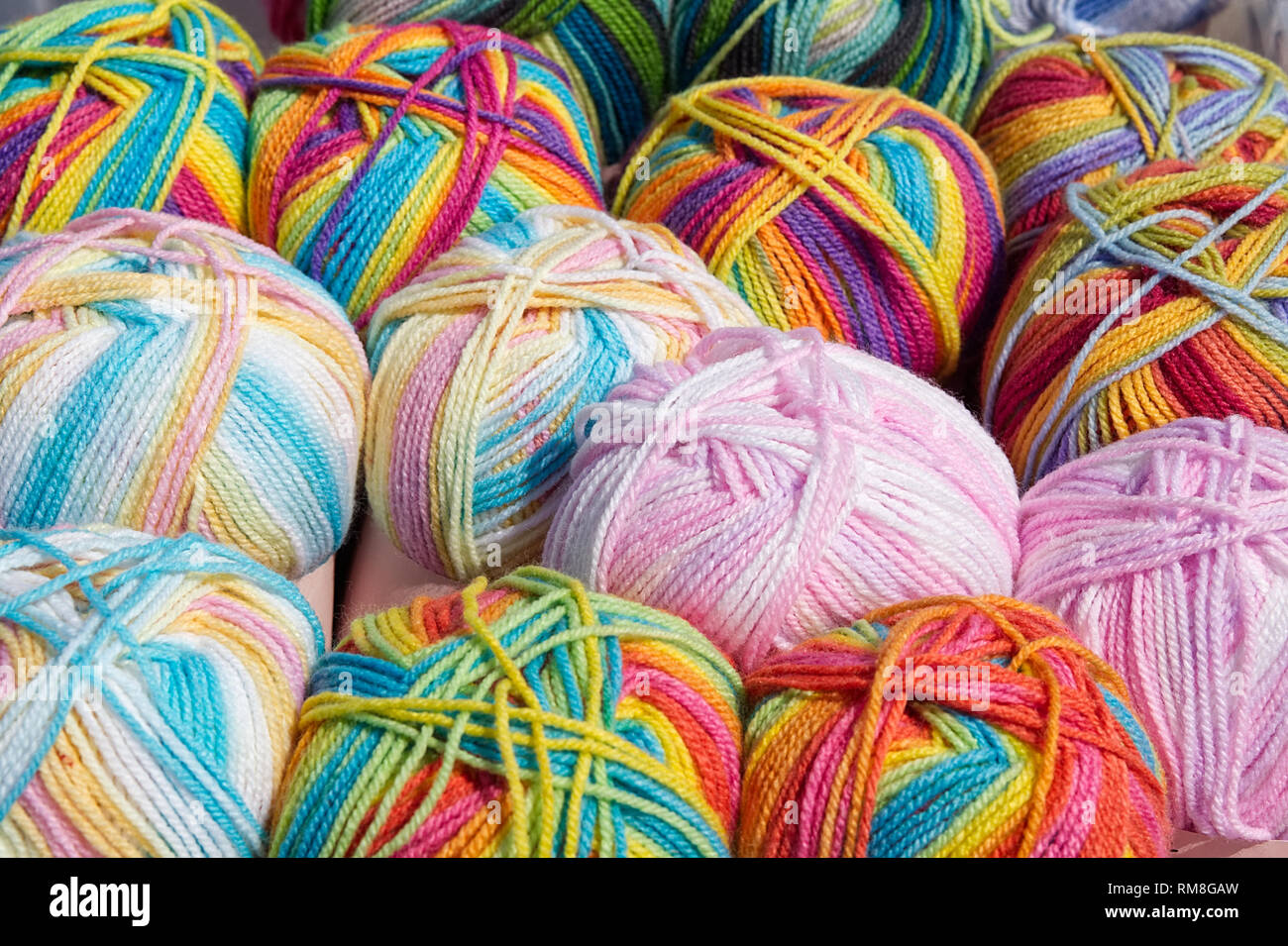 Balls of rainbow coloured and pink wools Stock Photo