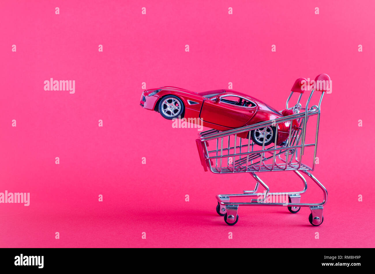 Car shopping concept. New red car in a shopping cart as a symbol for