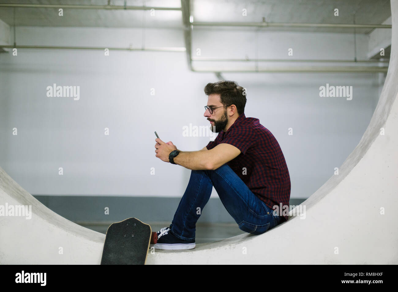 Hipster skater using smart phone in underground Stock Photo