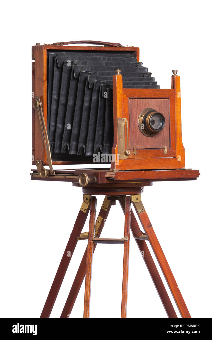 An antique bellows camera atop an old wooden tripod isolated on white Stock Photo