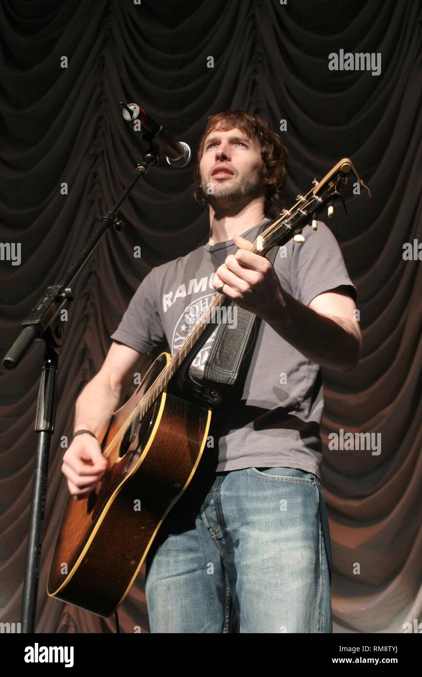 Musician James Blunt is shown playing an acoustic guitar during a solo concert performance. Stock Photo