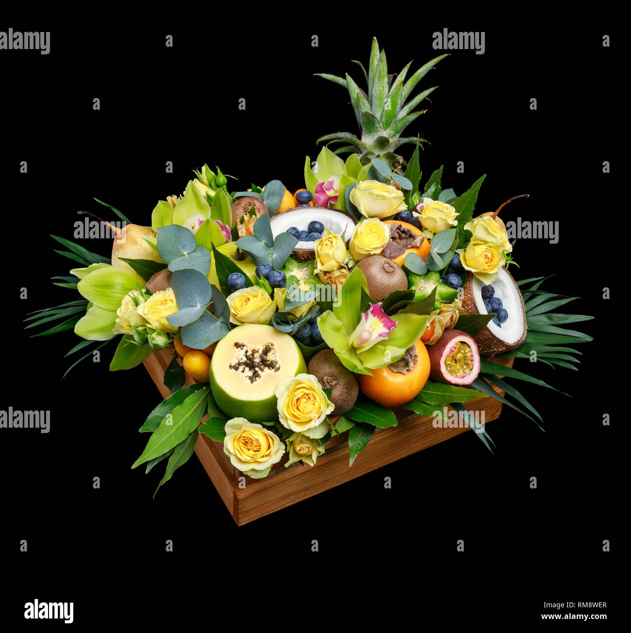 Wooden box with lots of exotic fruits and flowers isolated on black ...