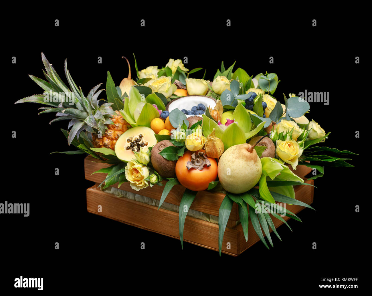 Wooden box with lots of exotic fruits and flowers isolated on black ...