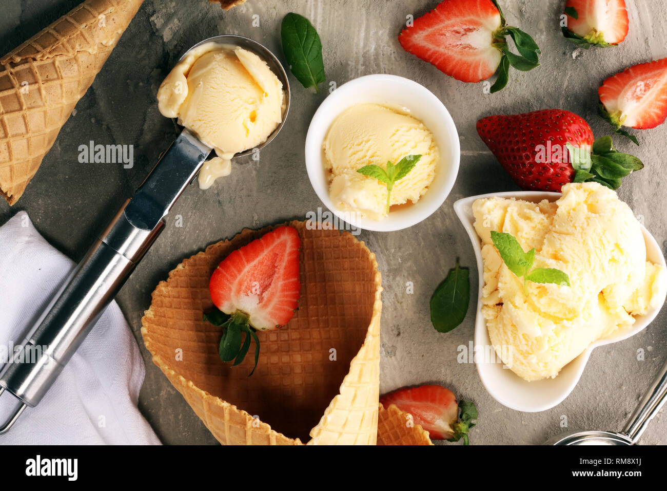 Vanilla ice cream scoop with fresh strawberries and icecream cones on a